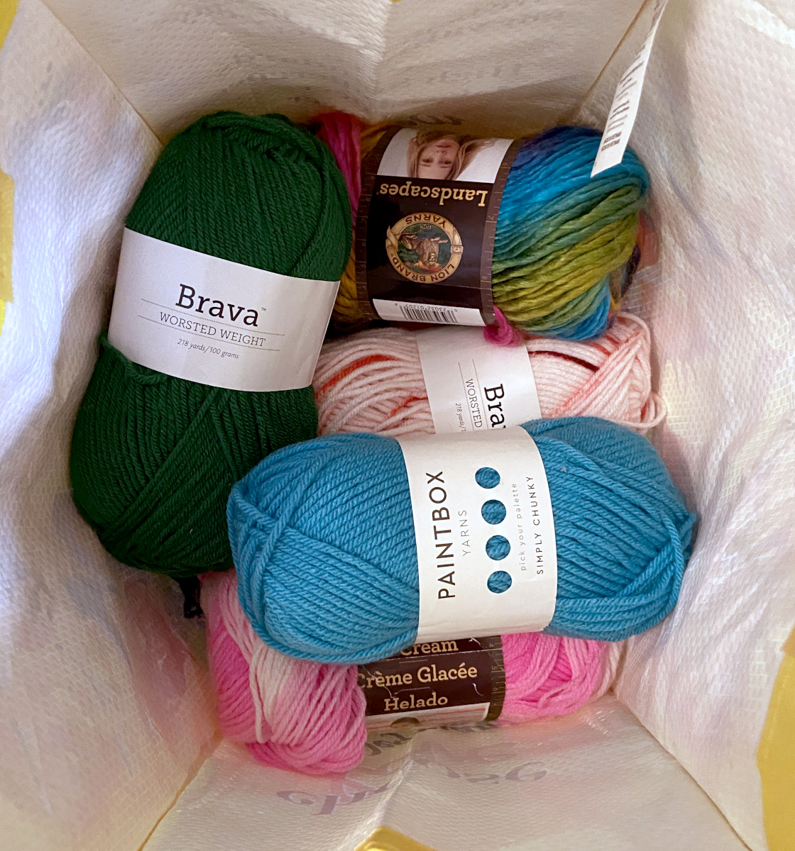 a shopping bag filled with multi-color skeins of yarn
